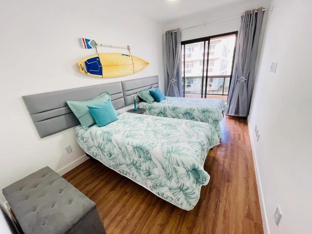 um quarto com uma cama e uma prancha de surf na parede em Apartamento Alto padrão na praia do forte em Cabo Frio