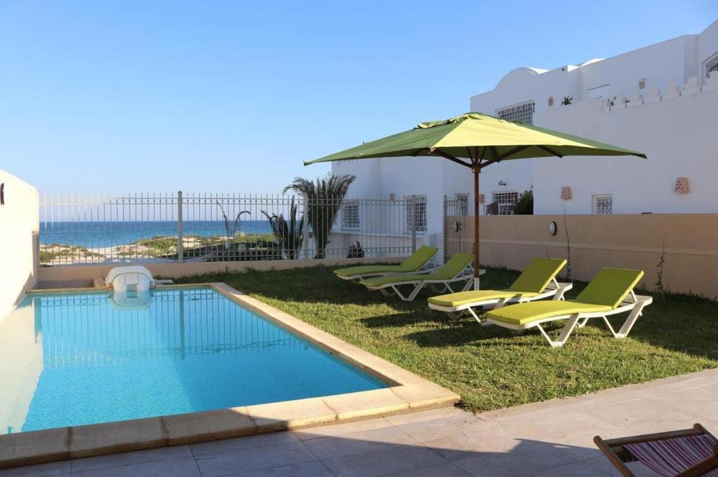 einen Pool mit Liegestühlen und einem Sonnenschirm in der Unterkunft DIAR SIDI VILLAS DE LUXE in Kelibia