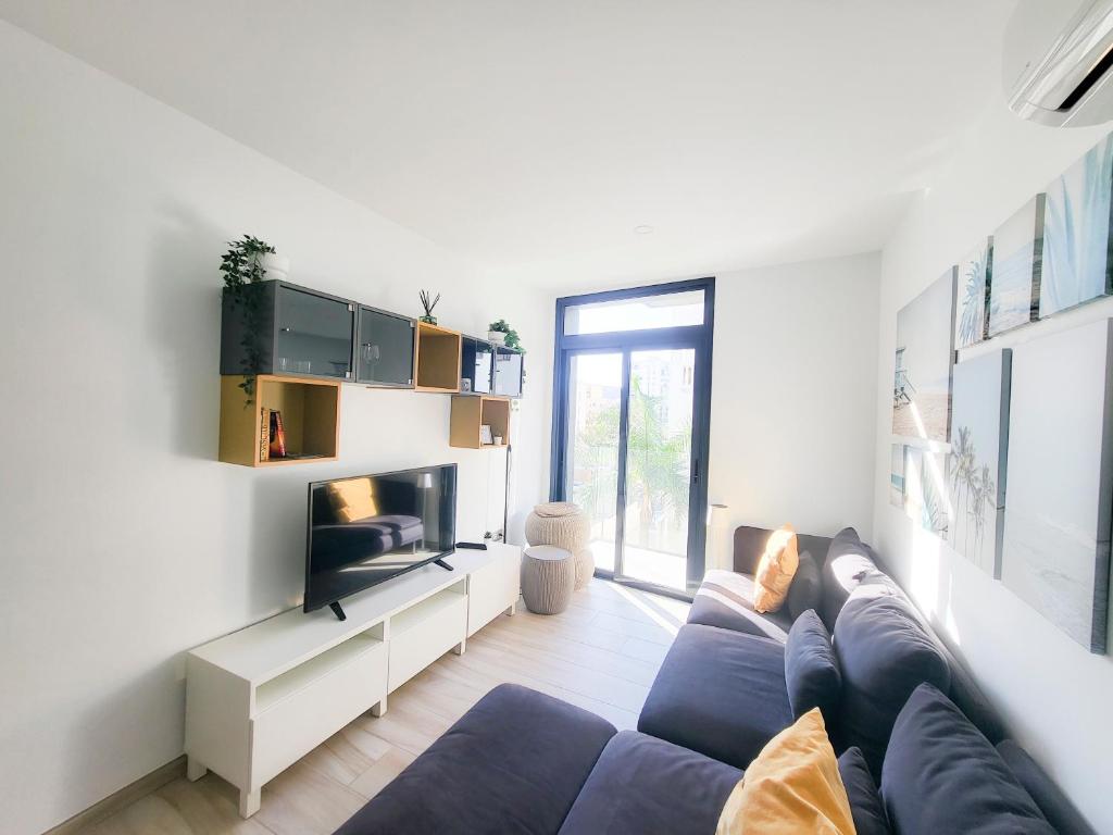 uma sala de estar com um sofá azul e uma televisão em Los Cristianos Ljus em Arona