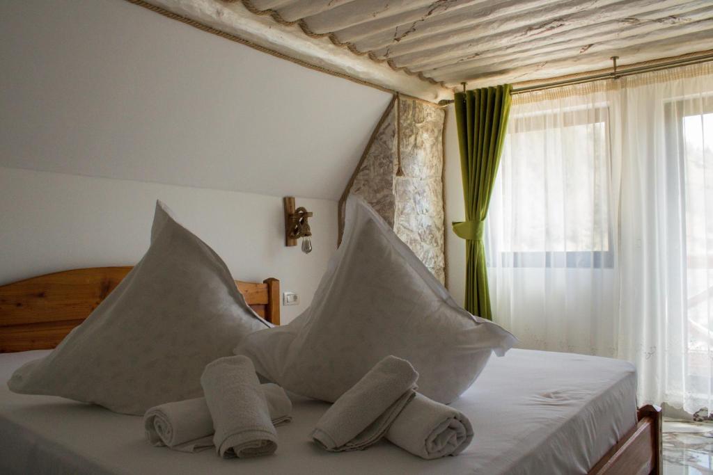 1 dormitorio con cama con almohadas y ventana en Vila katherina, en Moieciu de Sus