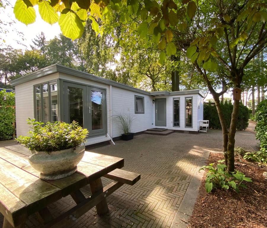 een klein wit huis met een picknicktafel en een bank bij Sfeervol Boschalet 5 persoons met Sauna in Voorthuizen