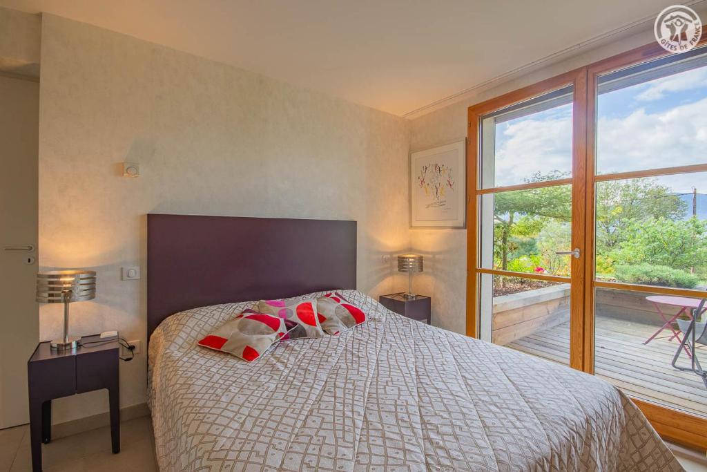 a bedroom with a bed and a large window at Les perrelles in Bellecombe-en-Beauges