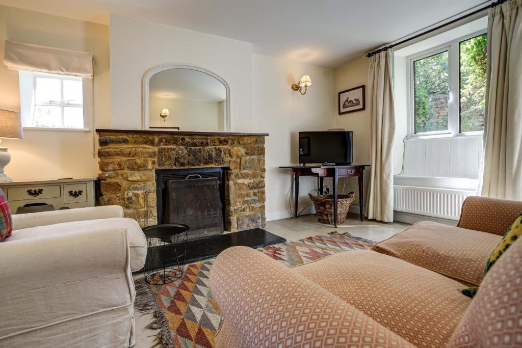 a living room with a couch and a fireplace at Rose Cottage in Adderbury