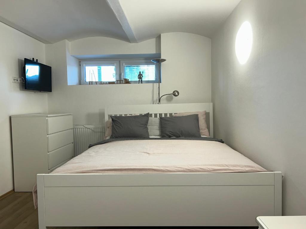 a white bedroom with a bed with a tv on it at Stromořadní 17 in Břeclav