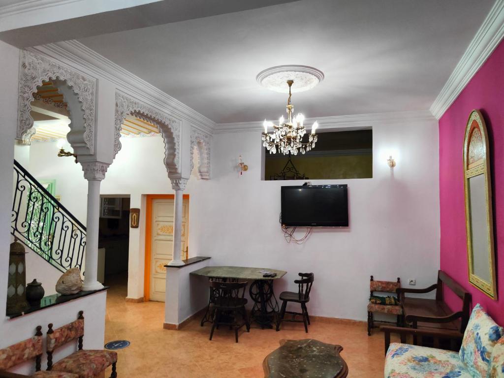 een woonkamer met een tafel en een tv aan de muur bij Dar Baddi in Marrakesh