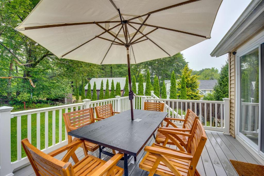 una mesa de madera con sillas y una sombrilla en el porche en Rye Coastal Retreat with Deck and Outdoor Dining en Rye