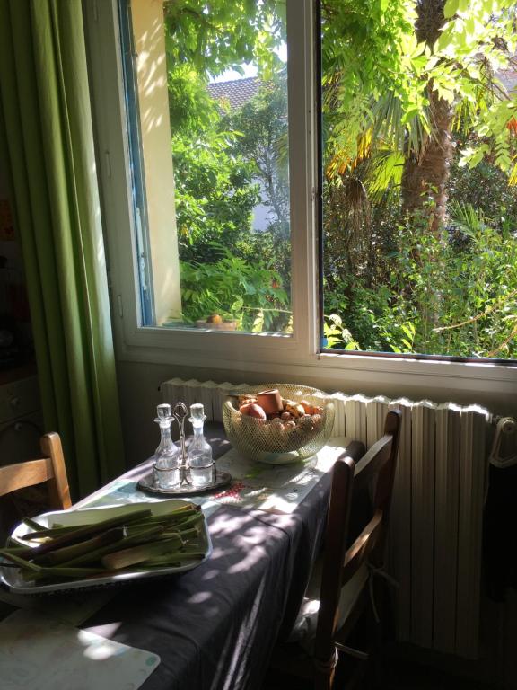 una mesa con un bol de fruta y una ventana en Chambre spacieuse et lumineuse en Mondeville