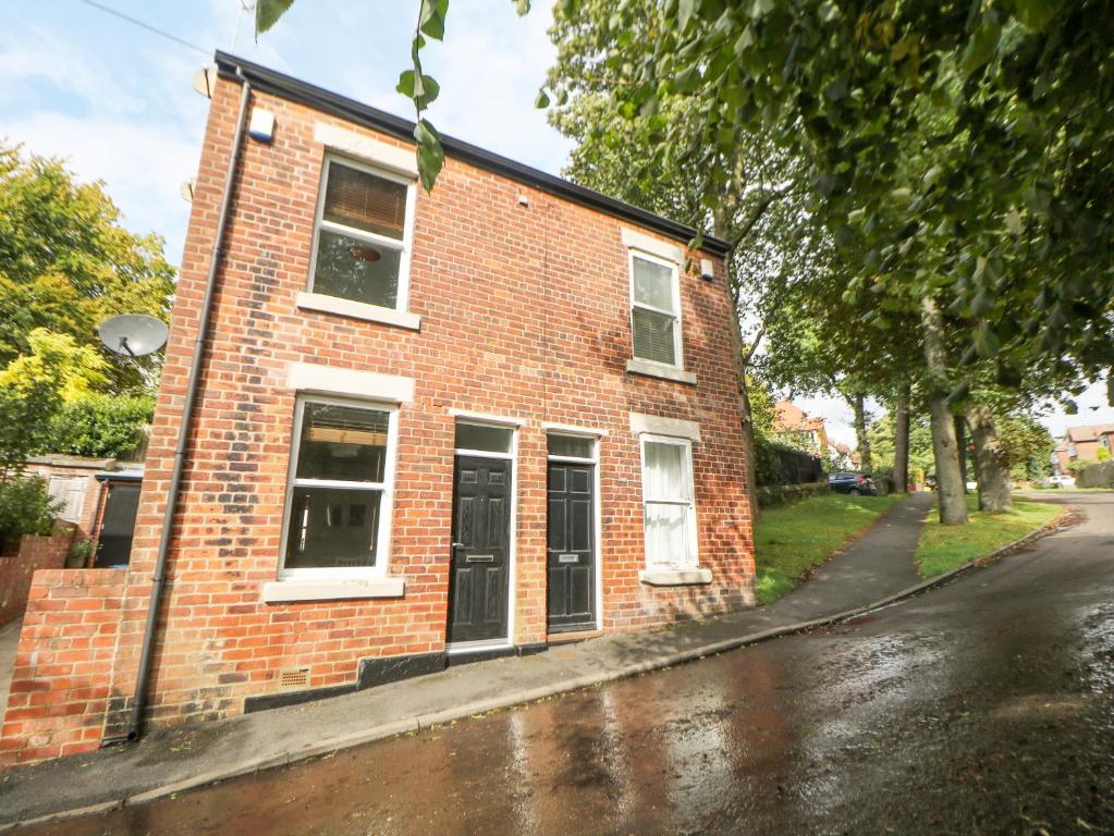 un edificio de ladrillo rojo en una calle con una calle empapada de lluvia en Potters Cottage en Sheffield