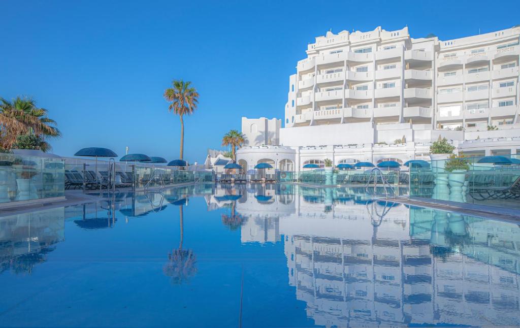 un hotel con piscina d'acqua di fronte a un edificio di Santa Barbara Golf and Ocean Club a San Miguel de Abona