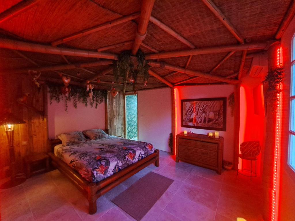 1 dormitorio con 1 cama en una habitación con luces rojas en Mas des rochers - Case bambou, en Le Beausset