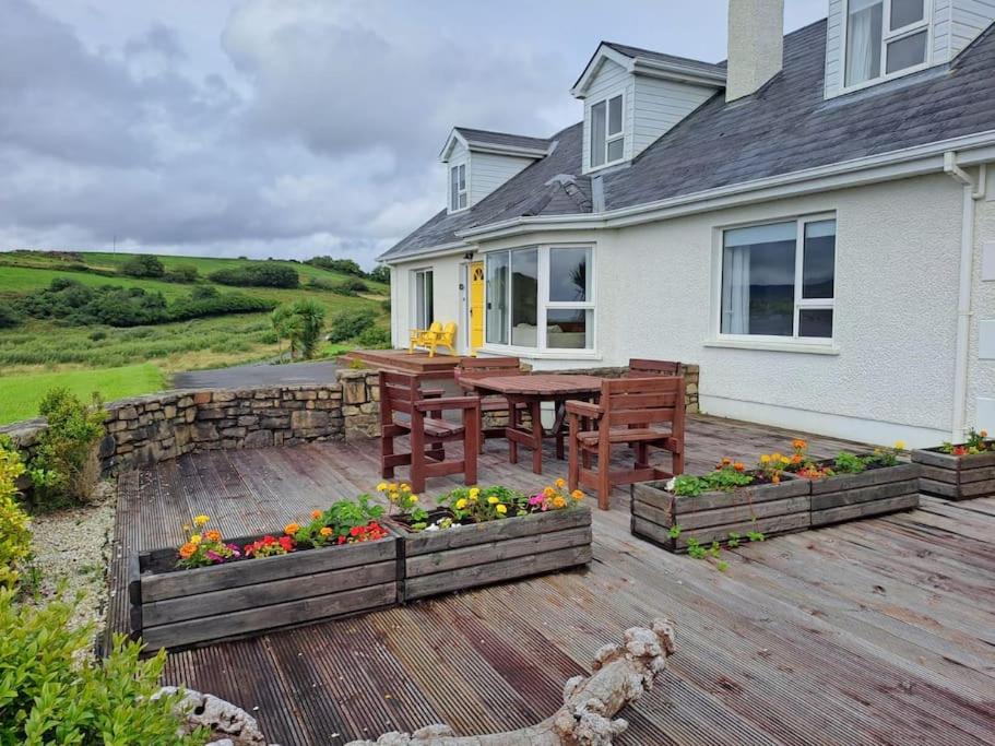 una terraza de madera con una mesa y flores en una casa en Buncronan Port Self Catering en Donegal
