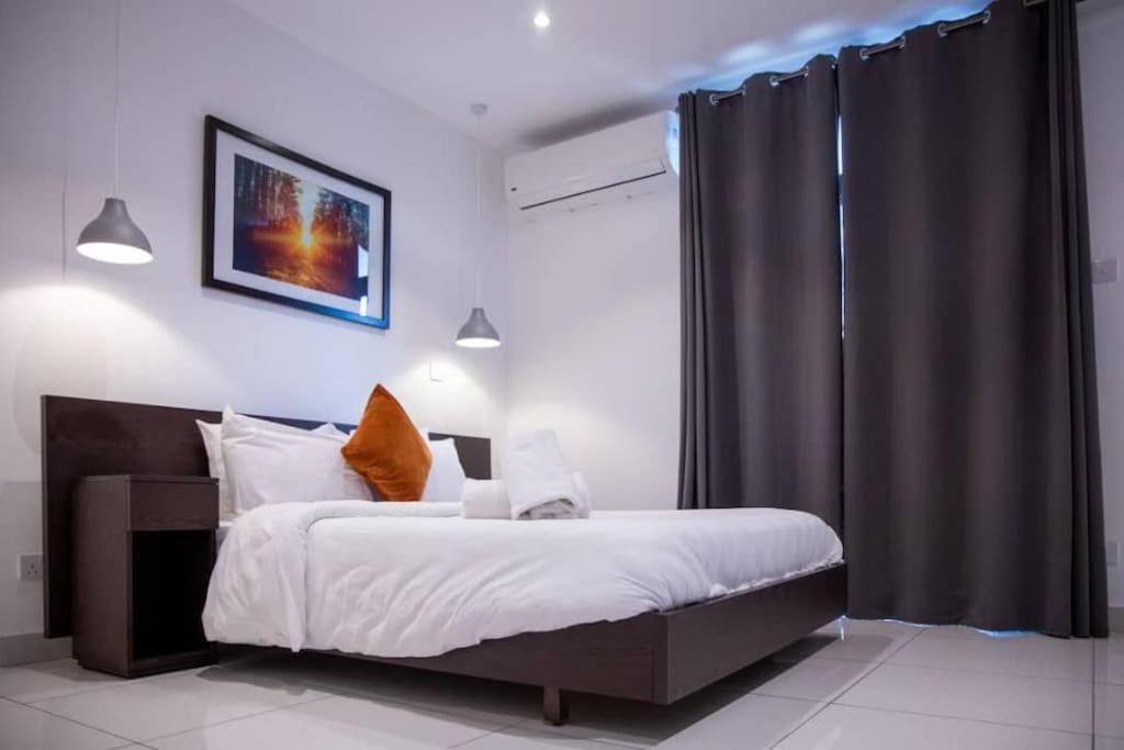een slaapkamer met een bed en een zwart gordijn bij Special 1 Bed Apt W/pool View @Embassy Gard 70m2 in Cantonments