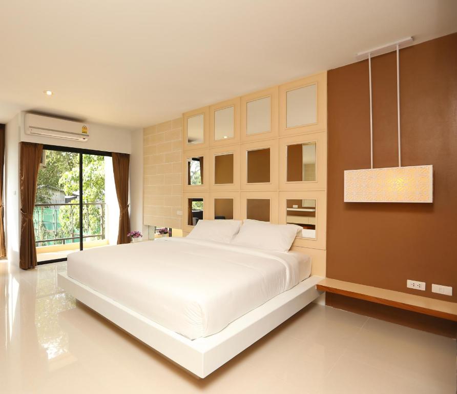 a large white bed in a room with a window at Naka Residence in Phuket