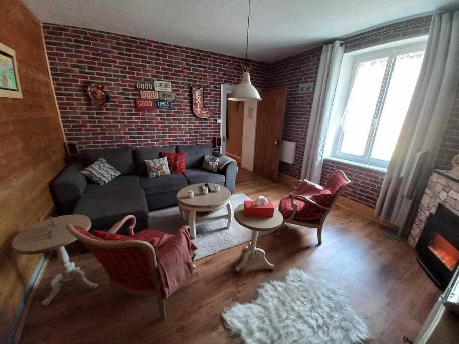 een woonkamer met een bank en een bakstenen muur bij Gite de l'Ours in Saint-Maurice-sur-Moselle