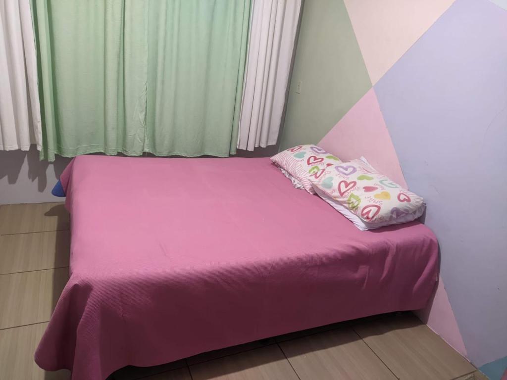 uma pequena cama com um lençol cor-de-rosa e uma almofada em CASA PARA OKTOBERFEST 12 PESSOAS. em Blumenau