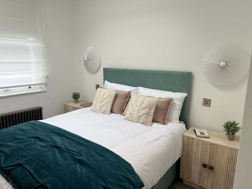 a bedroom with a bed with a green headboard and pillows at Gorgeous newly refurbished 2 bedroom apartment in London in London