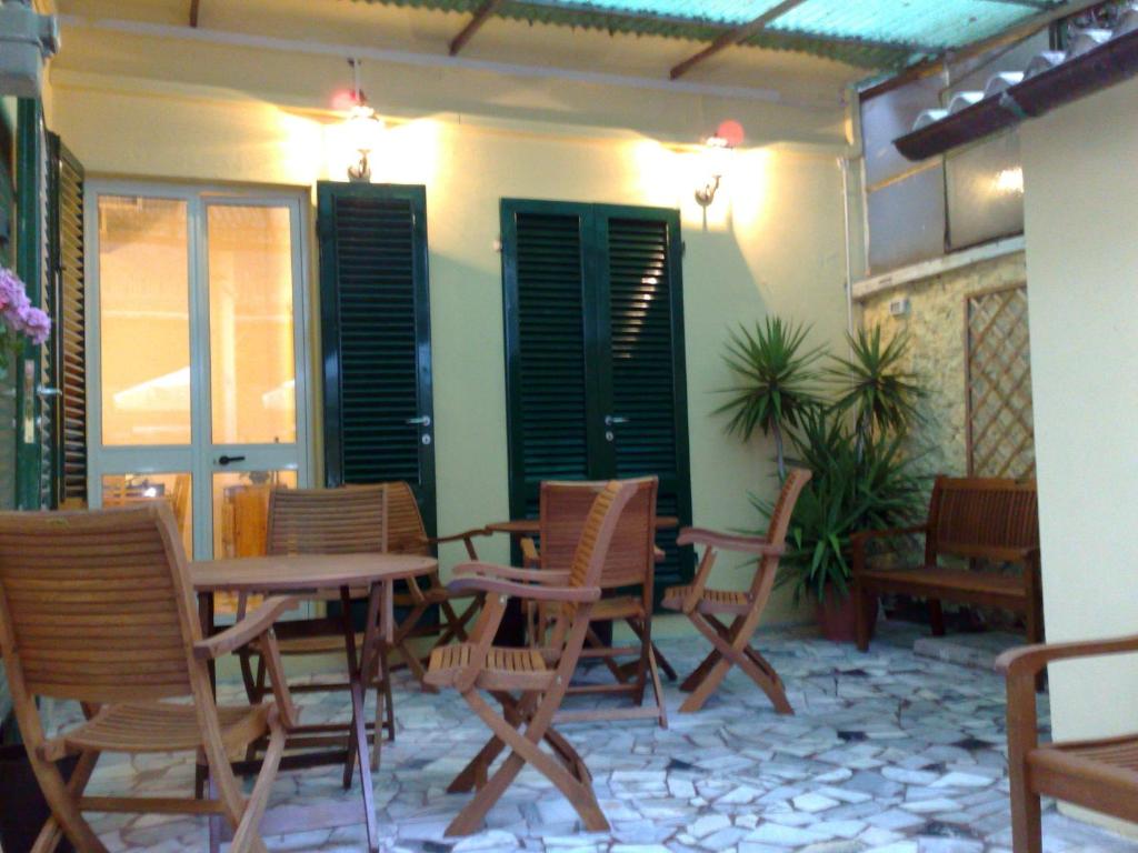 un patio con mesas, sillas y persianas verdes en Apartments Viareggio, en Viareggio