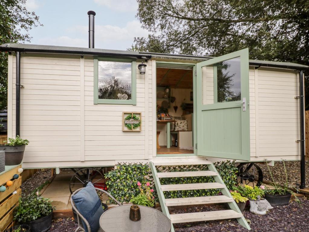 una casa pequeña con una puerta verde y una mesa en Cobblers Cabin, en Northampton
