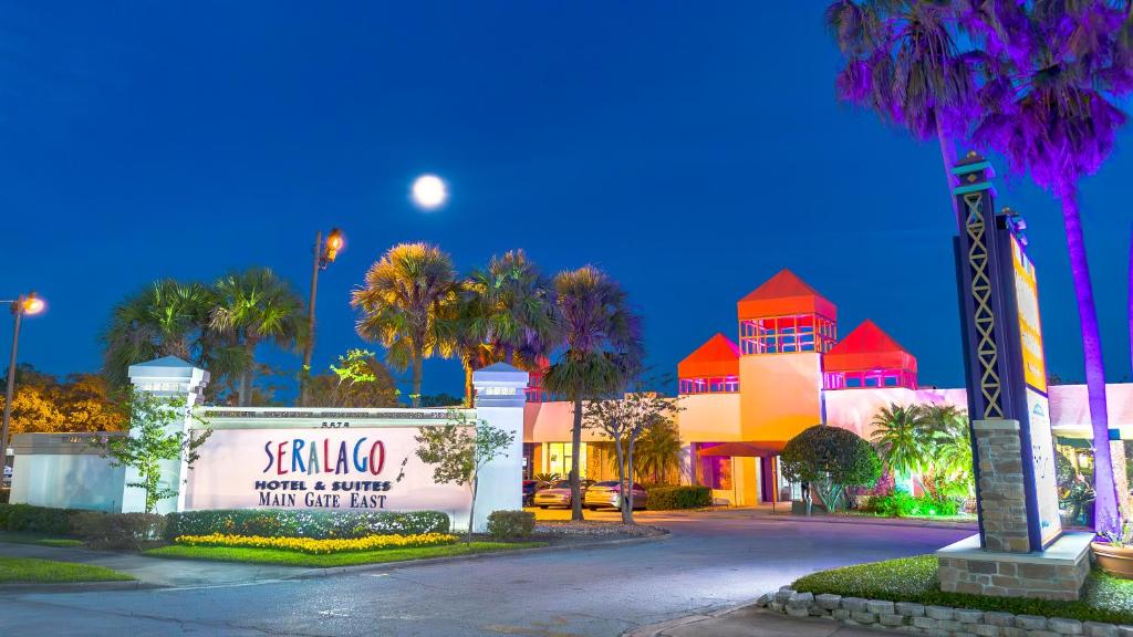 um sinal em frente a um edifício com palmeiras em Seralago Hotel & Suites Main Gate East em Orlando