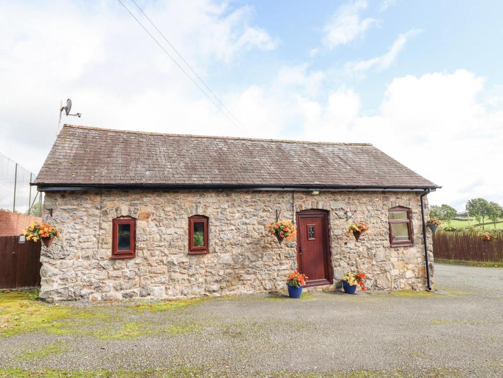 een klein stenen gebouw met een rode deur bij Bwthyn Ty Newydd in Pont Dolanog