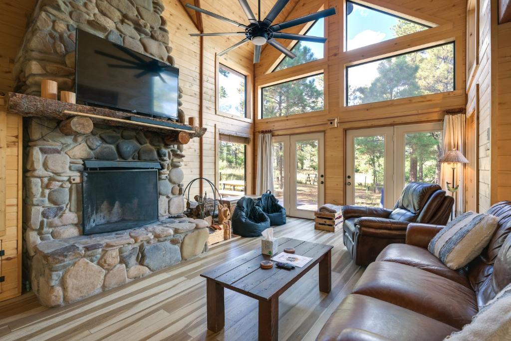 sala de estar con chimenea de piedra y muebles de cuero en Spacious and Quiet Pagosa Springs Cabin with Deck!, en Pagosa Springs