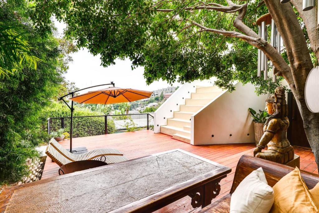 a patio with a table and an umbrella at LA Nature Retreat with Rooftop Deck and Dtwn Views! in Los Angeles