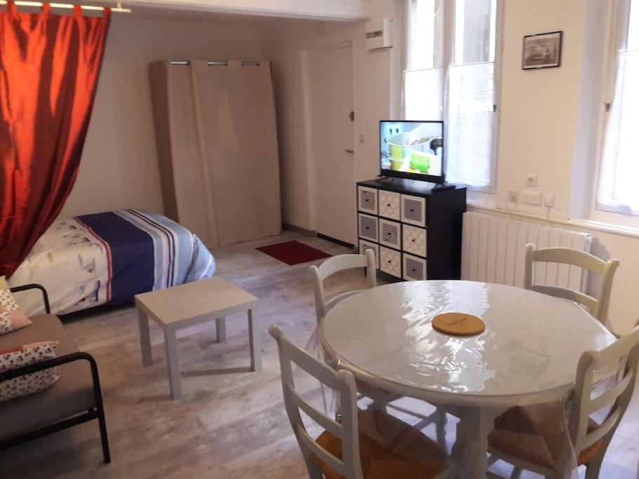- un petit salon avec une table et une chambre dans l'établissement Charmant Studio Meublé (en plein centre de Dieppe), à Dieppe