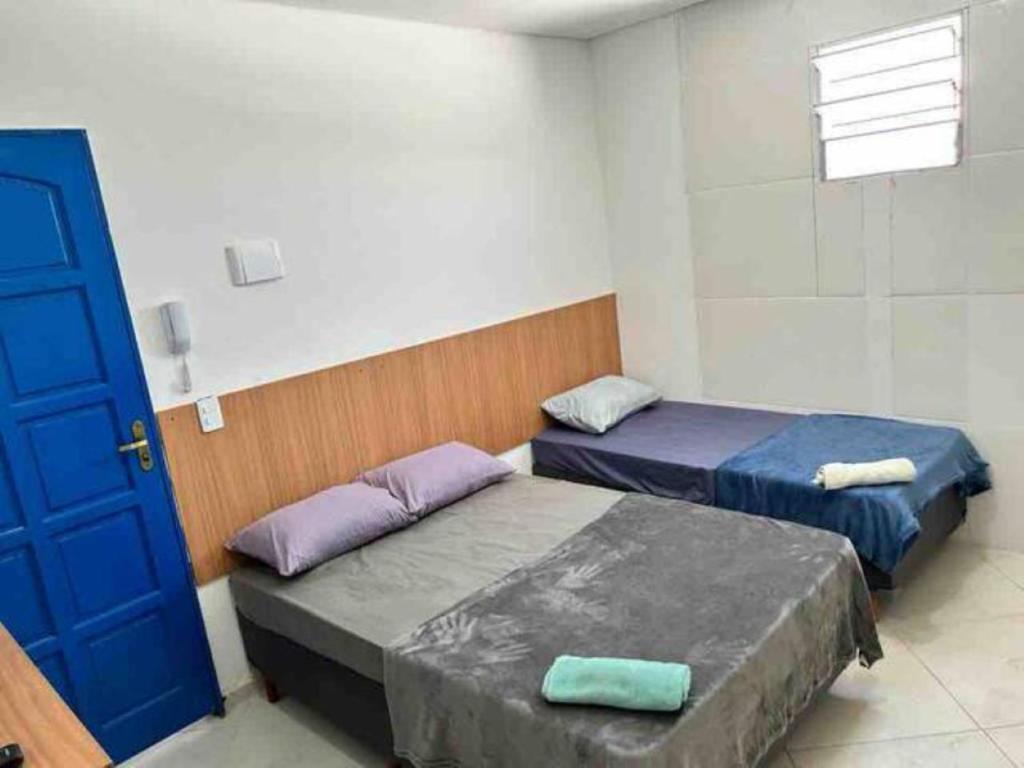 two beds in a room with a blue door at Studio em São Paulo - Expo Center Norte in São Paulo