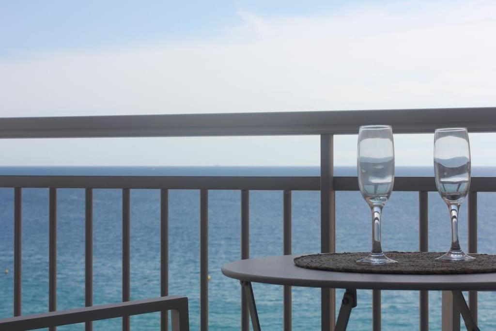 zwei Weingläser auf einem Tisch auf einem Balkon in der Unterkunft Apartamento primera línea de mar in Platja  d'Aro