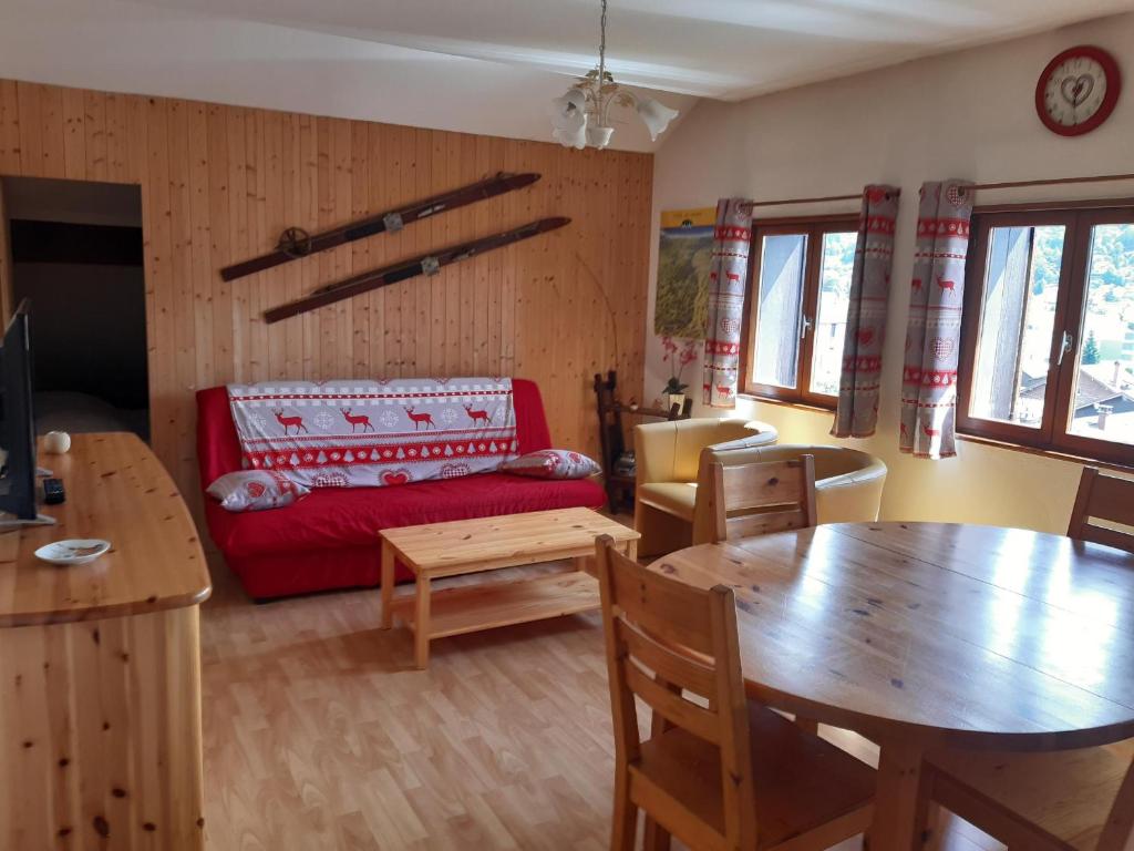 a living room with a table and a red couch at Appartement Le Parad'hiver in Gérardmer