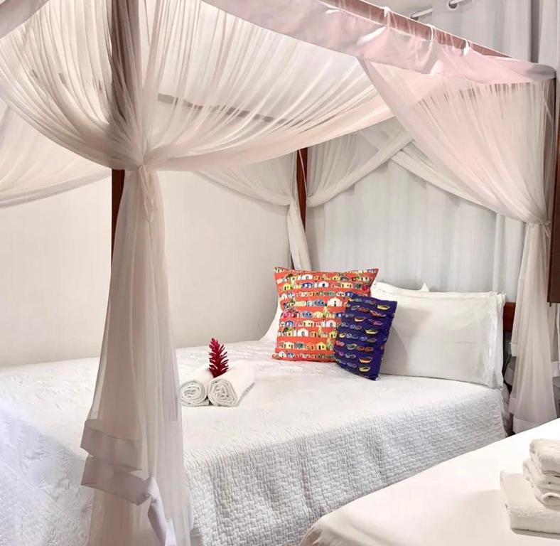 uma cama branca com dossel num quarto em Cantinho da Cineka em Caraíva
