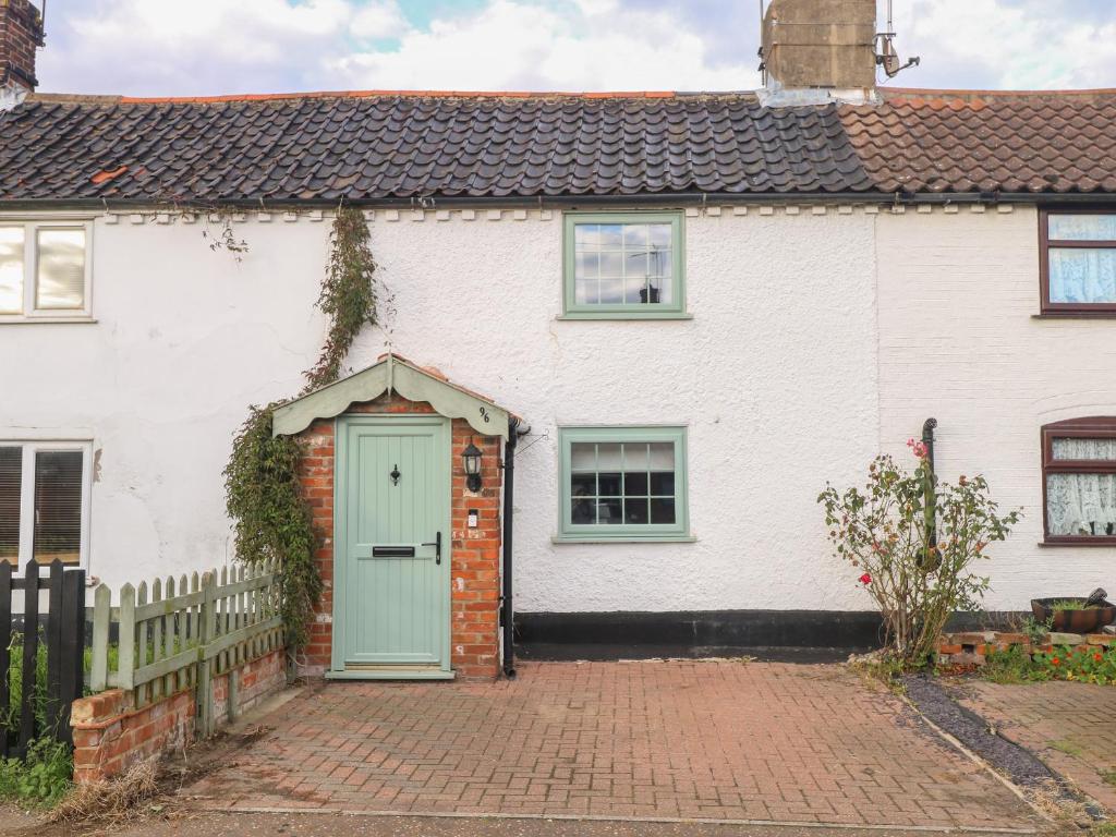 a white house with a green door at Vintner's Cottage in Norwich