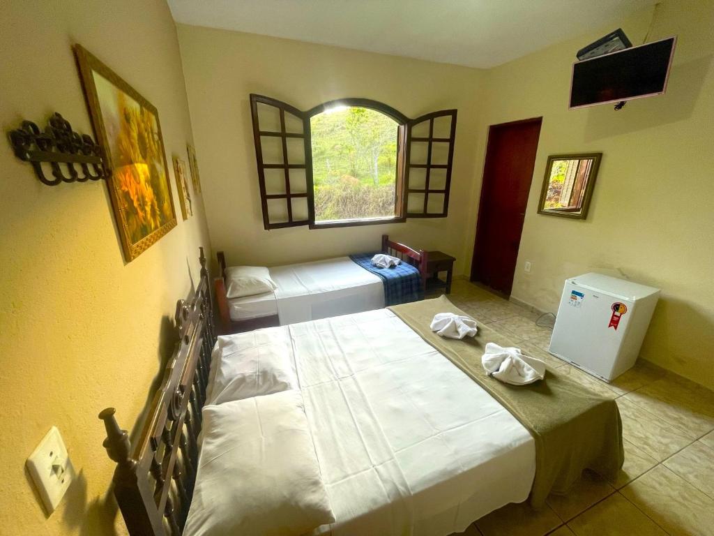 1 dormitorio con 2 camas y ventana en Hotel Fazenda Villa Verona, en Serra Negra