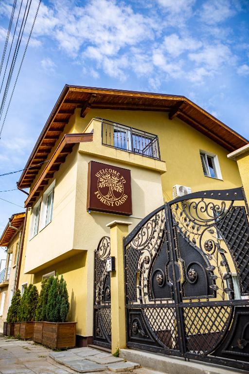 a yellow house with a black gate in front of it at Forest Oasis Guest House FREE PARKING in Sapareva Banya