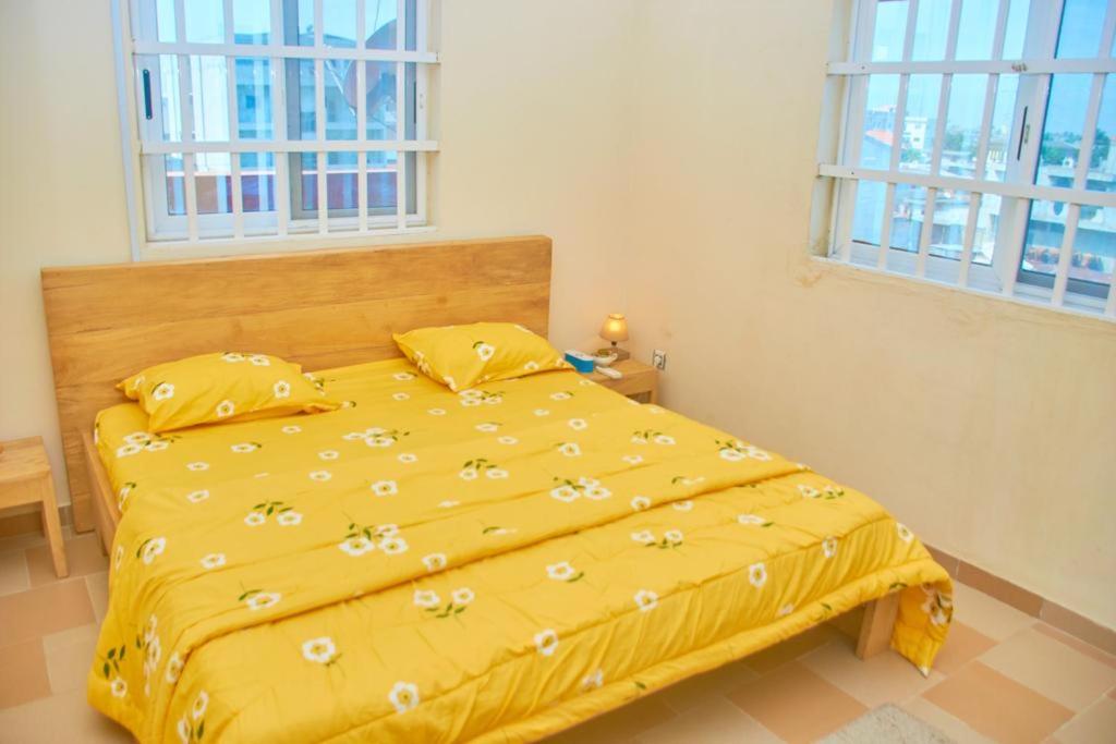 a yellow bed in a bedroom with two windows at Agim-Cotonou in Cotonou