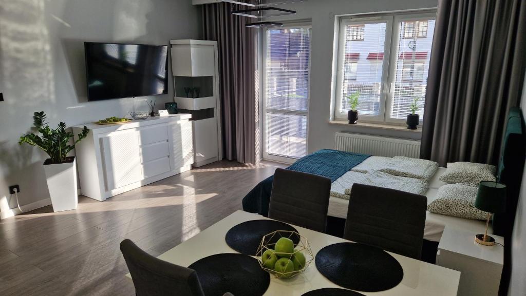 - un salon avec un lit et une table avec des chaises dans l'établissement Apartament Gimnazjalna Prestige, à Końskie