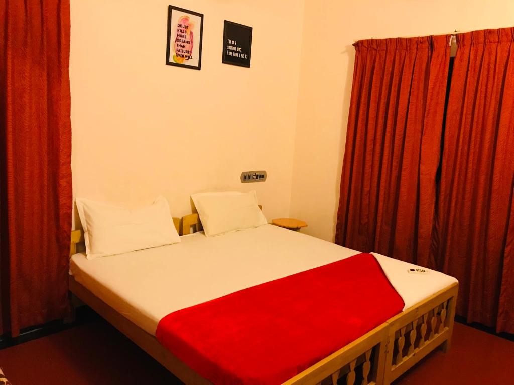 Cama en habitación con cortinas rojas en OCEAN PEARL RESIDENCY en Kochi