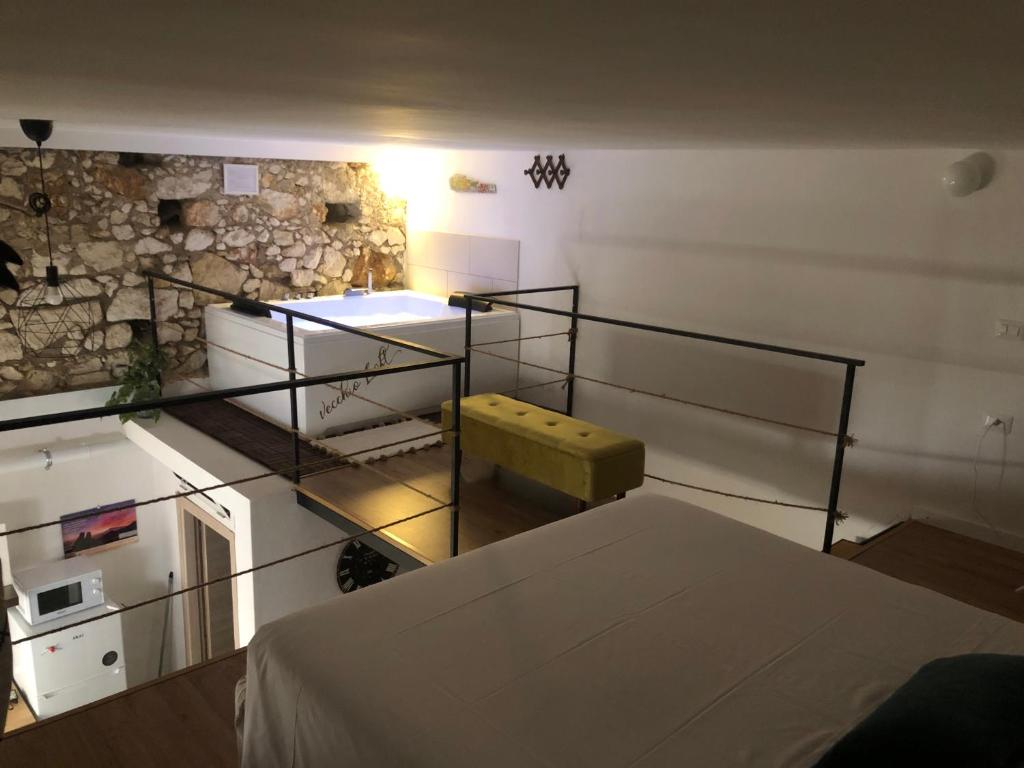 a room with a bed and a stone wall at Vecchio Loft con Jacuzzi in Siracusa