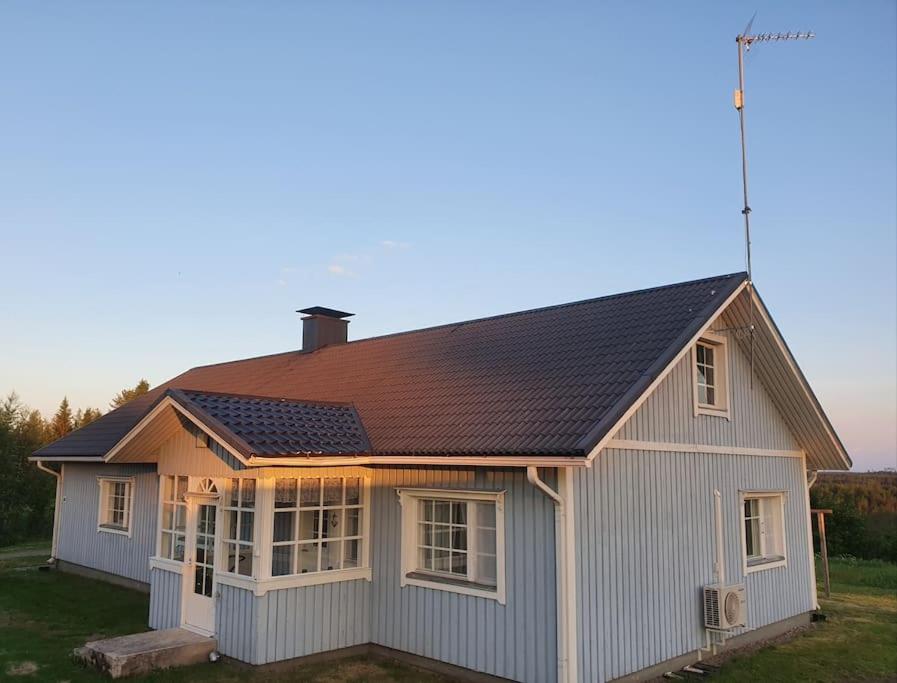 una pequeña casa blanca con techo marrón en Vanha maalaistila, en Kuhmo