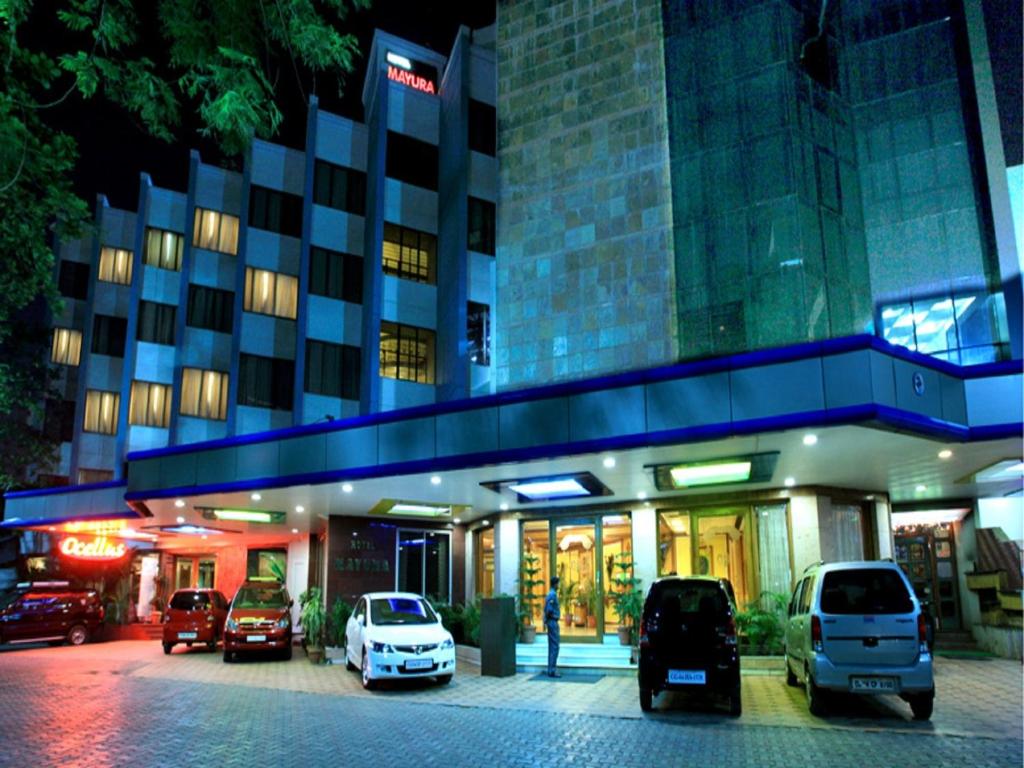 Hotel Mayura في رايبور: مبنى فيه سيارات تقف امامه