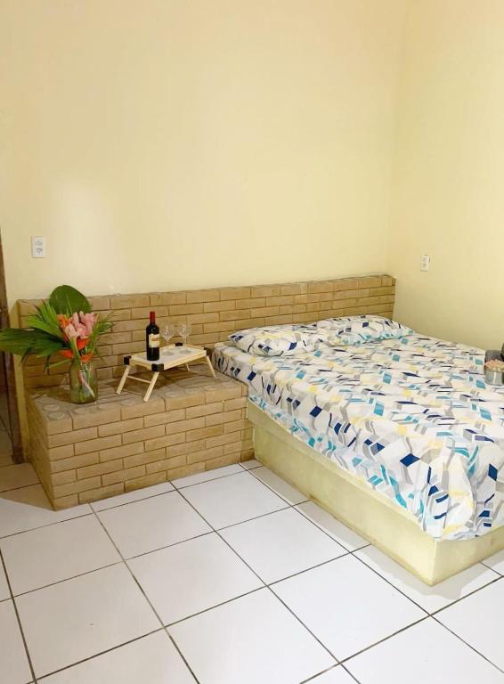 um quarto com uma cama e uma mesa com um vaso de flores em Suite Apoena 1 em Pacoti