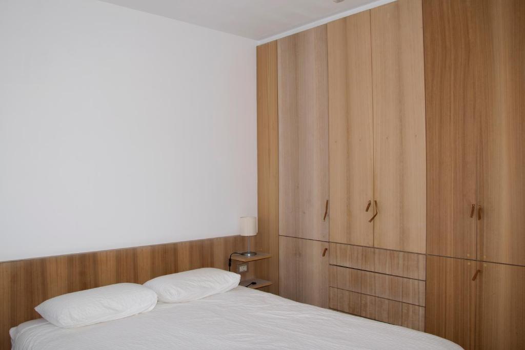 a bedroom with a white bed and wooden cabinets at Apartamento de Mar y Playa en Illa de Arousa in Isla de Arosa