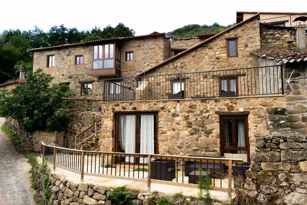 Casa de piedra antigua con balcón en una calle en Ecolagar O Barqueiro, en Pantón