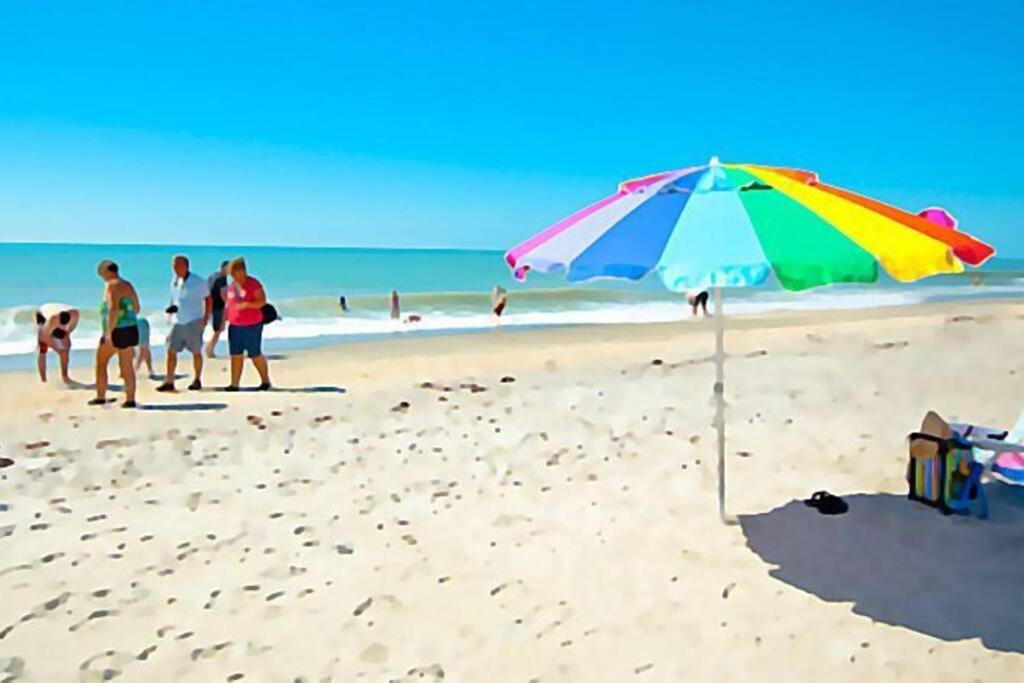 a beach with a colorful umbrella and people on the beach at Gorgeous Private Pool! Fountains! Near Beach- Os in Venice