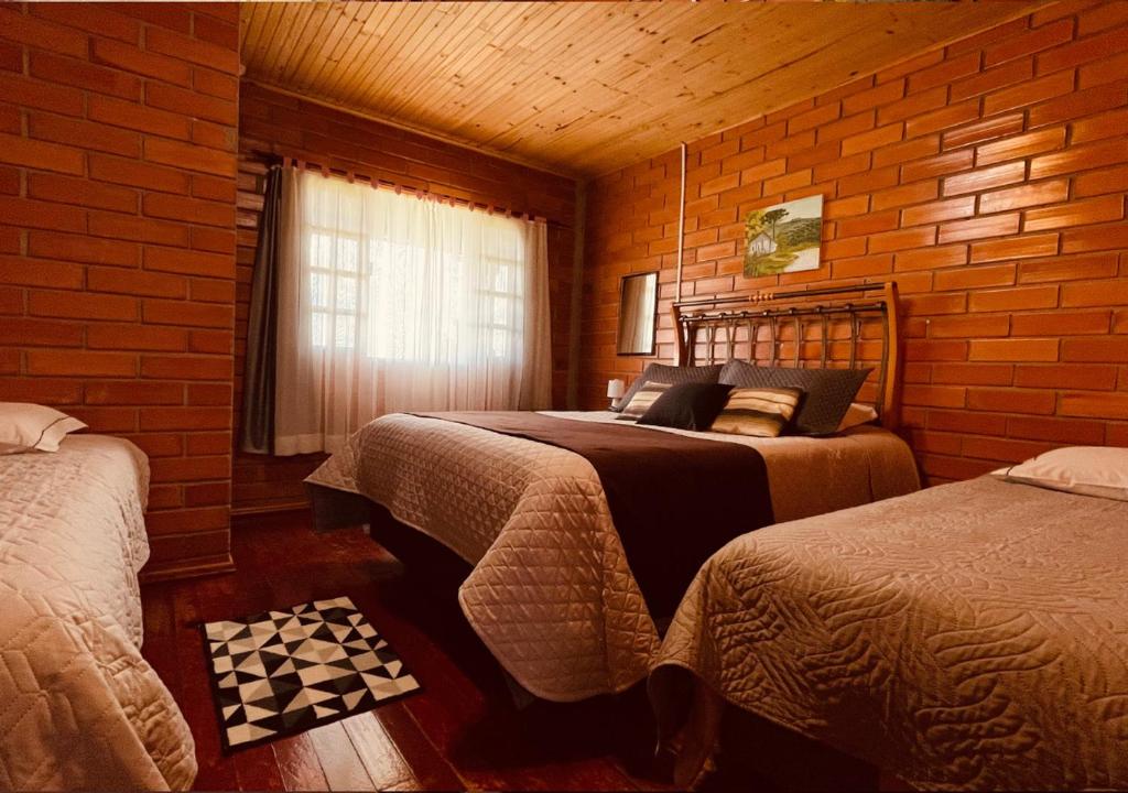 1 dormitorio con 2 camas y pared de ladrillo en Fazenda Santa Rita Turismo Rural en Bom Jardim da Serra