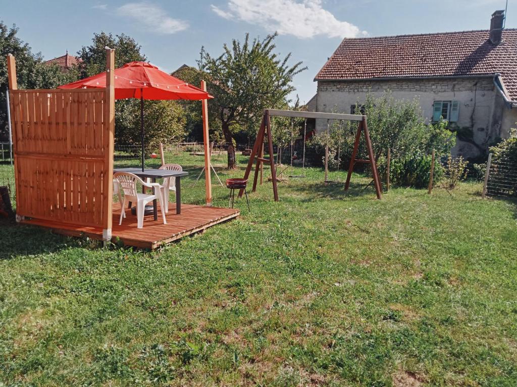 une terrasse en bois avec une table et un parasol dans l'établissement Charmant Gite 4 Places dans le Jura, à Marigny