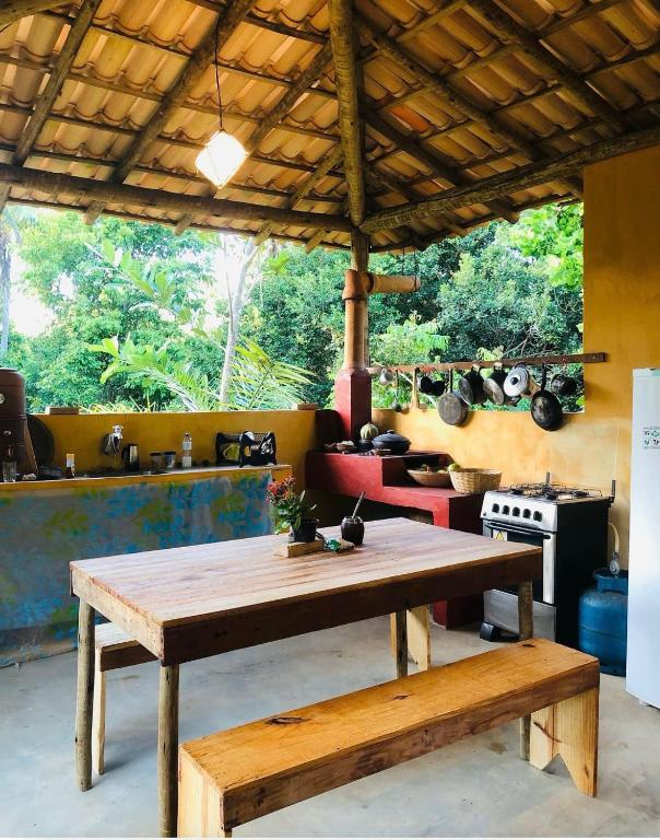 a kitchen with a wooden table and a stove at Casa da Roça- Casa completa e jardim privativo in Mata de Sao Joao