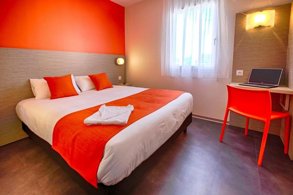 1 dormitorio con cama y escritorio con ordenador portátil en Hôtel Formules Club 2, en Cenon