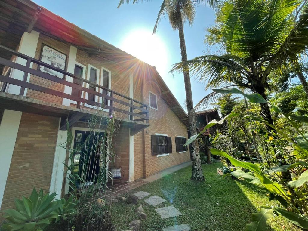 una casa con palmeras delante en Casa Rústica Alemã - 50m da praia en Ubatuba