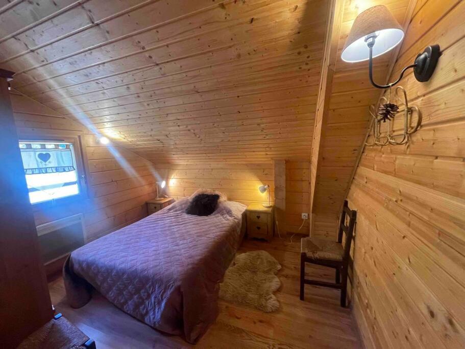 a bedroom with a bed in a wooden room at La joue du loup Bord des pistes - Chalet en bois de charme pour 10 personnes in Le Dévoluy